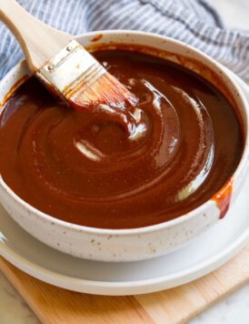 Bowl of bbq sauce with a basting brush resting in the sauce.