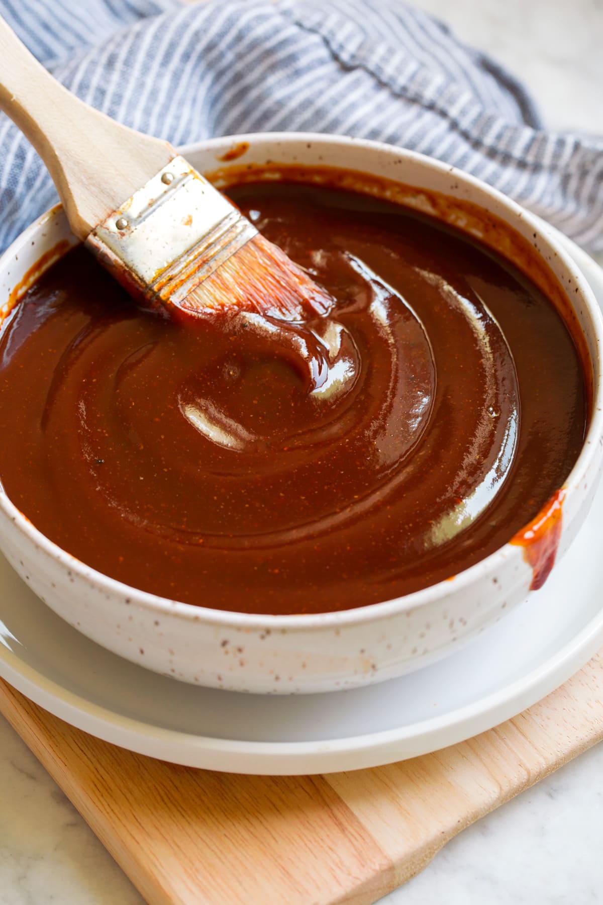 Bowl of bbq sauce with a basting brush resting in the sauce.