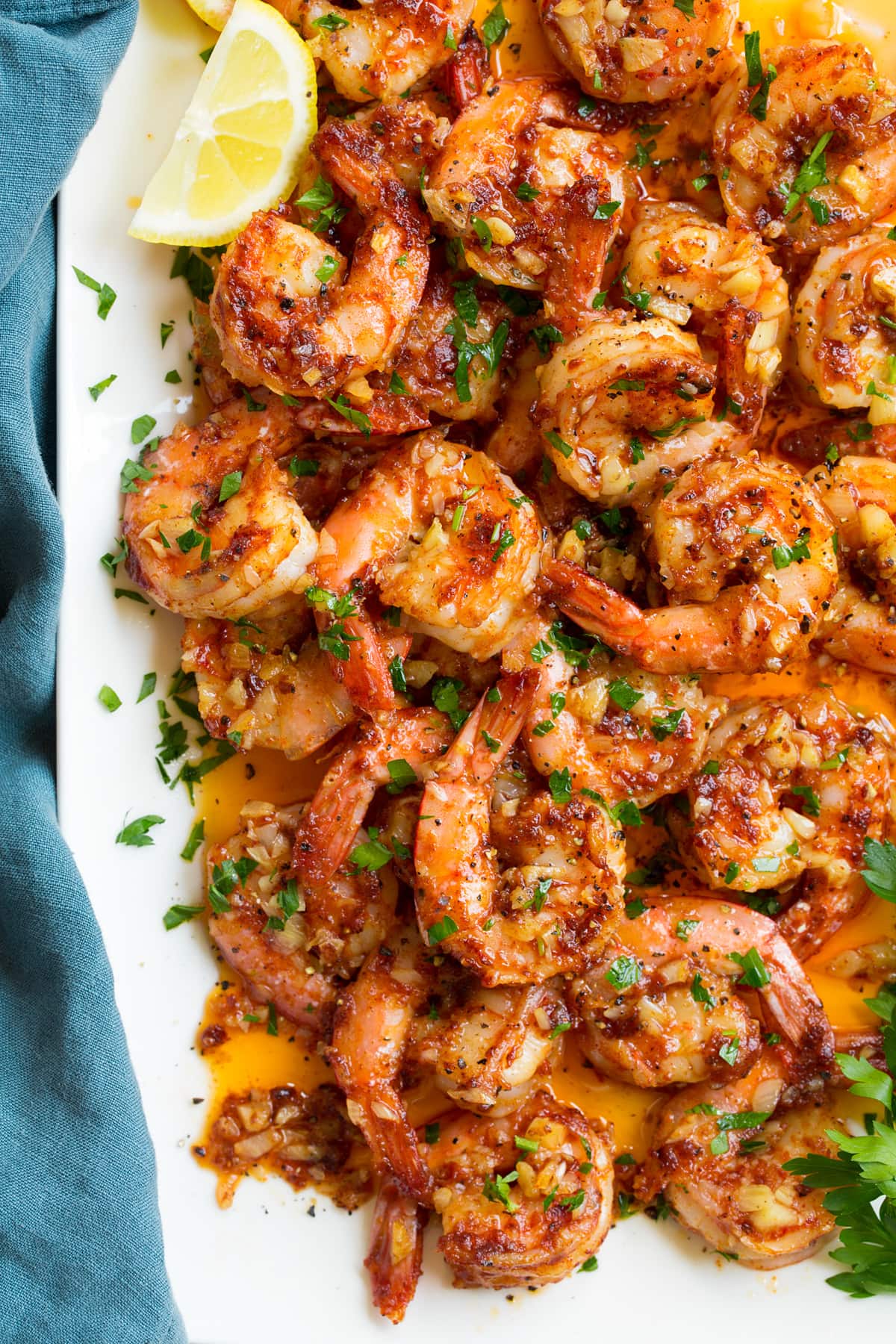 Close up overhead image of Hawaiian garlic shrimp on a white platter with the butter sauce.