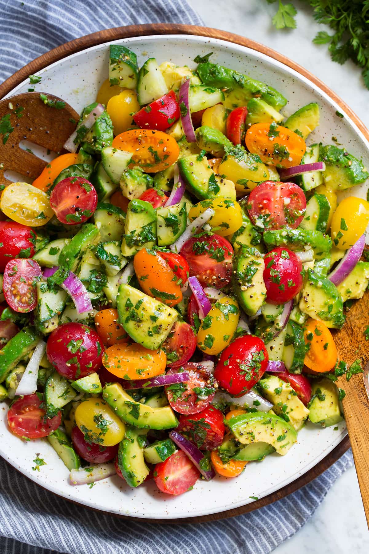 Avocado salad with fresh avocados, grape tomatoes, red onion, cucumbers and fresh herbs in a serving bowl.