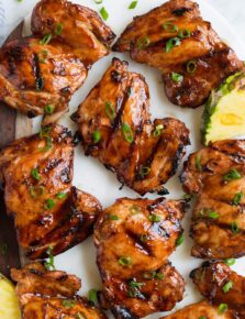 Close up image of huli huli chicken thighs on a platter. Shown overhead.