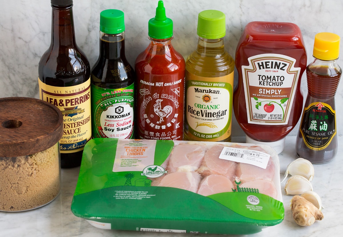 Image of ingredients used to make hawaiian huli huli chicken. Includes chicken thighs, brown sugar, Worcestershire sauce, soy sauce, sriracha, rice vinegar, ketchup, sesame oil, ginger and garlic.