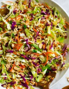 Close up overhead image of Asian ramen noodle salad in a large white salad bowl set over a marble surface.