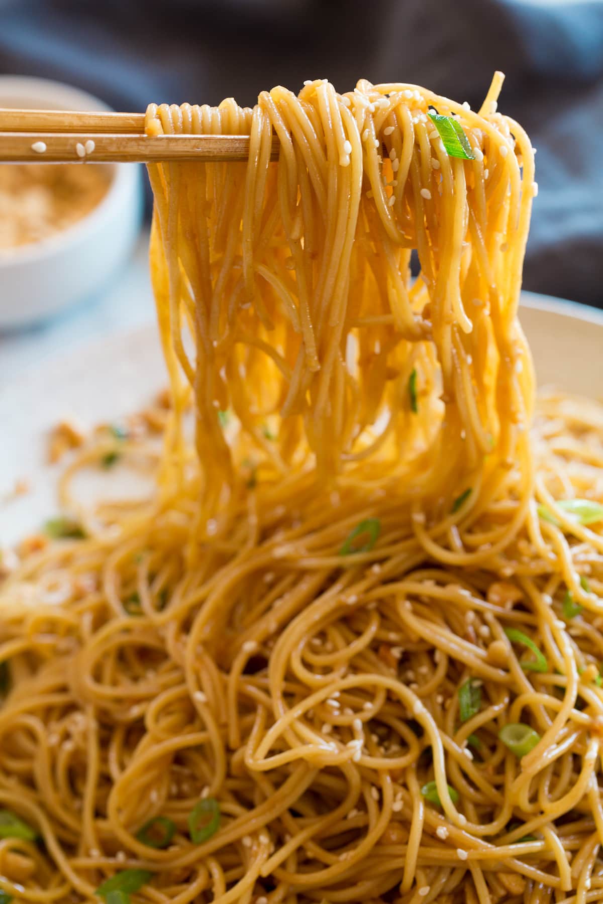 Photo: Sesame noodles shown close hanging over chopsticks.