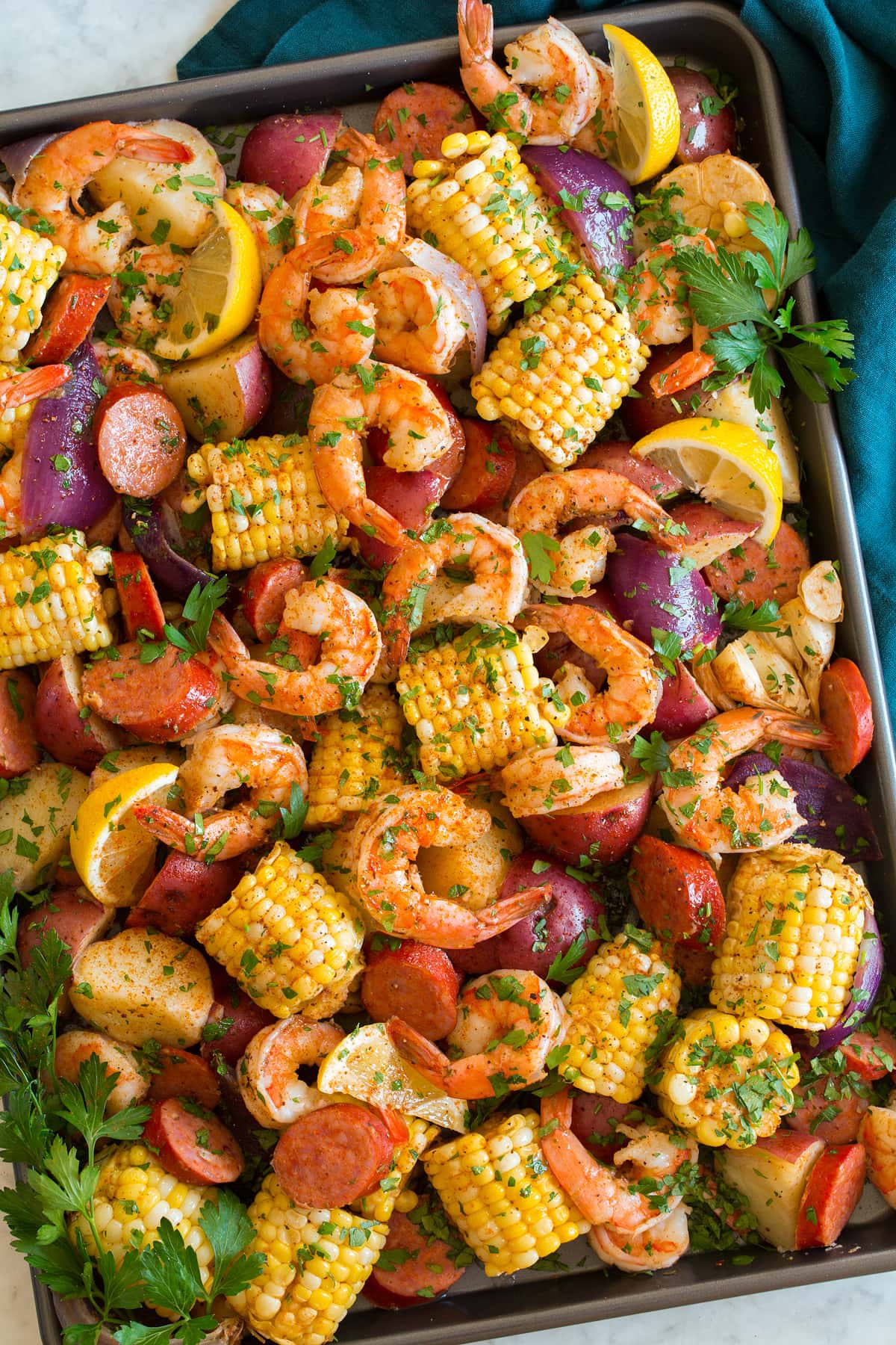 Image shown overhead of shrimp boil after cooking poured out and spread onto a large baking sheet.