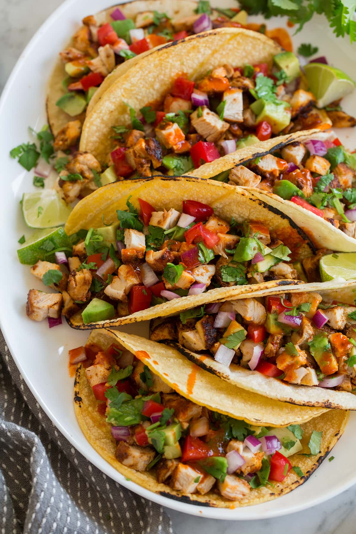 Chicken tacos on a platter shown from a side angle.