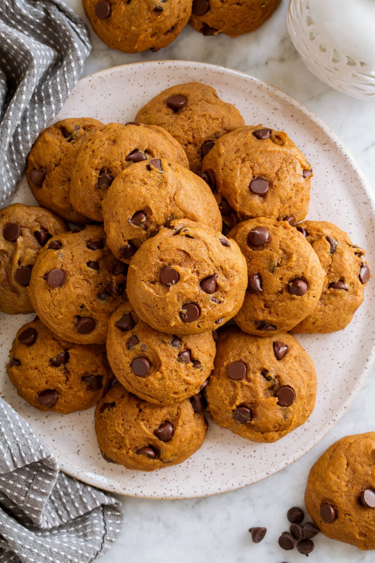 Pumpkin Chocolate Chip Cookies stacked on a plate and shown overhead.