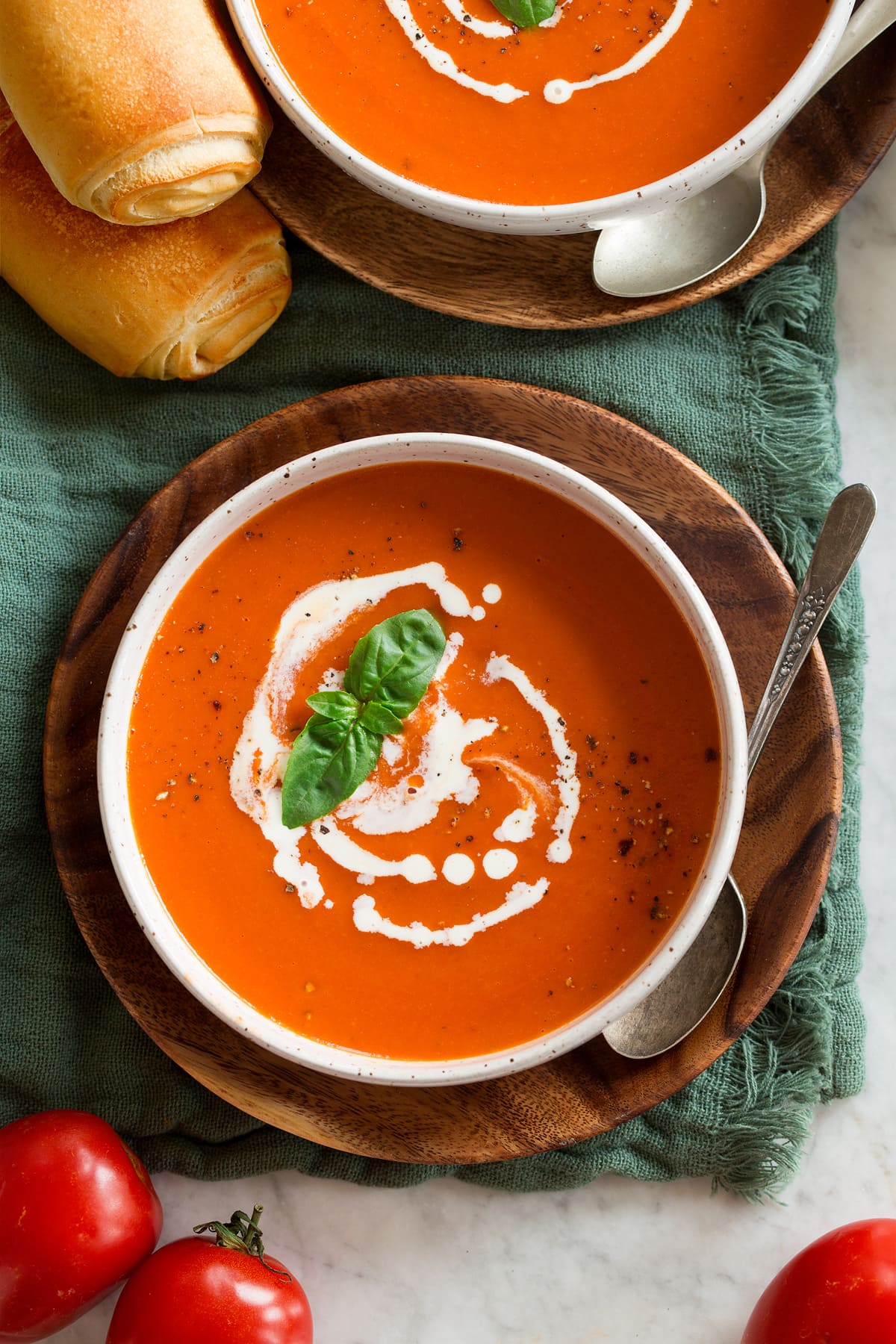 Overhead image of serving of tomato soup swirled with heavy cream.