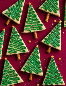 Triangular decorated Christmas tree cookies shown on a red surface.