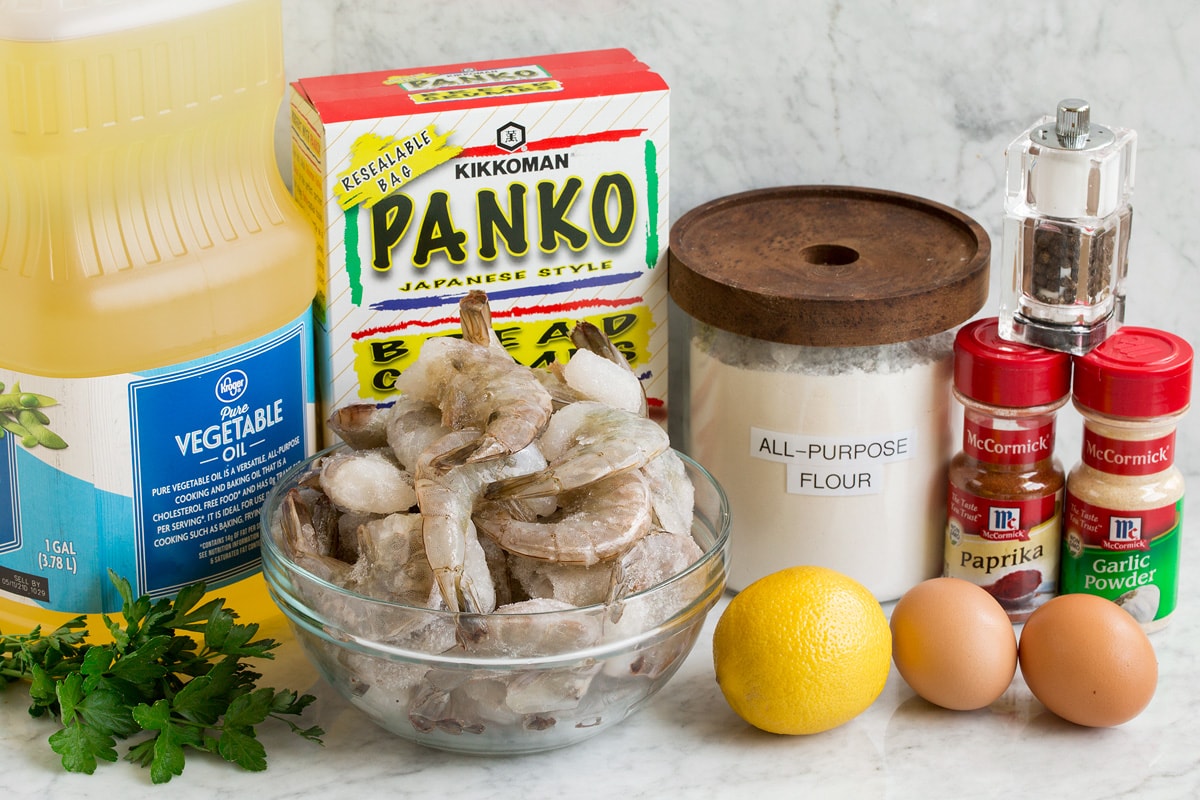 Photo of ingredients used to make fries shrimp. Includes shrimp, vegetable oil, panko bread crumbs, flour, eggs, garlic powder, paprika, salt, pepper, parsley and lemon.