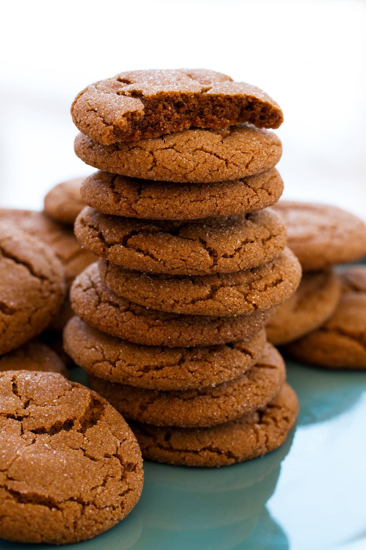 Tall stack of molasses cookies with the top cookie broken in half to show soft moist texture of interior.