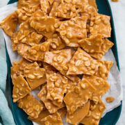 Peanut Brittle shown from above on a rectangular blue platter covered with parchment paper.