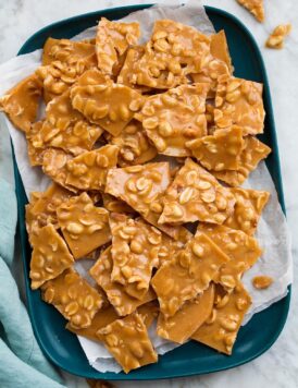 Peanut Brittle shown from above on a rectangular blue platter covered with parchment paper.