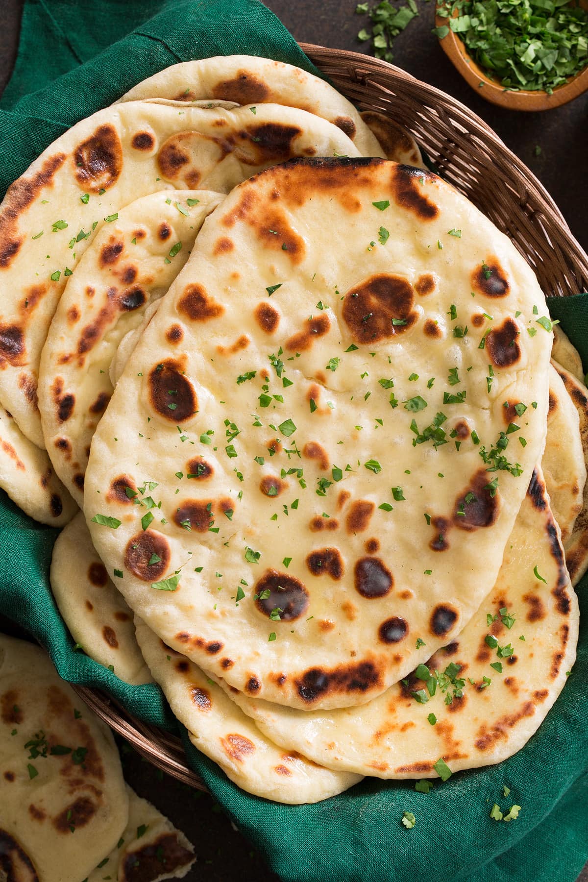 Homeamde naan layered in a basket with a green cloth.