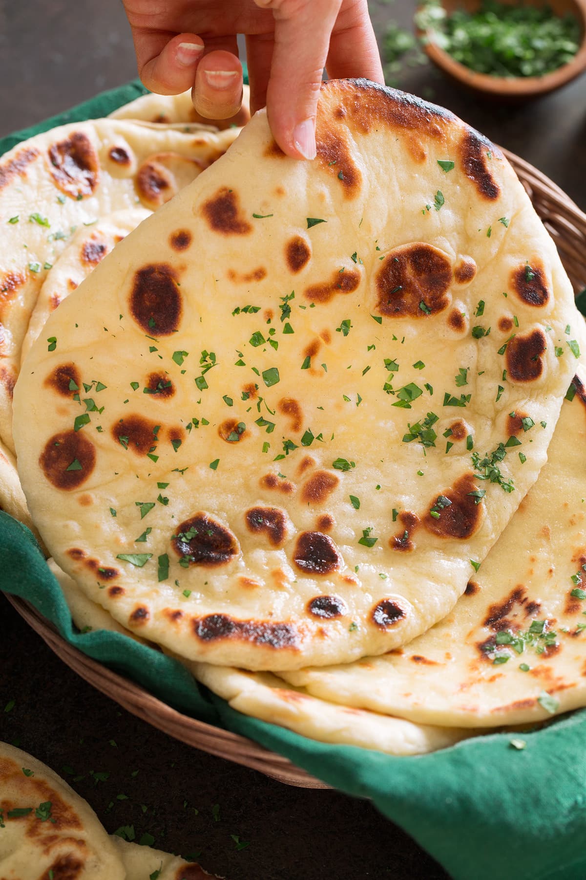 Photo of hand lifting soft naan bread from basket.