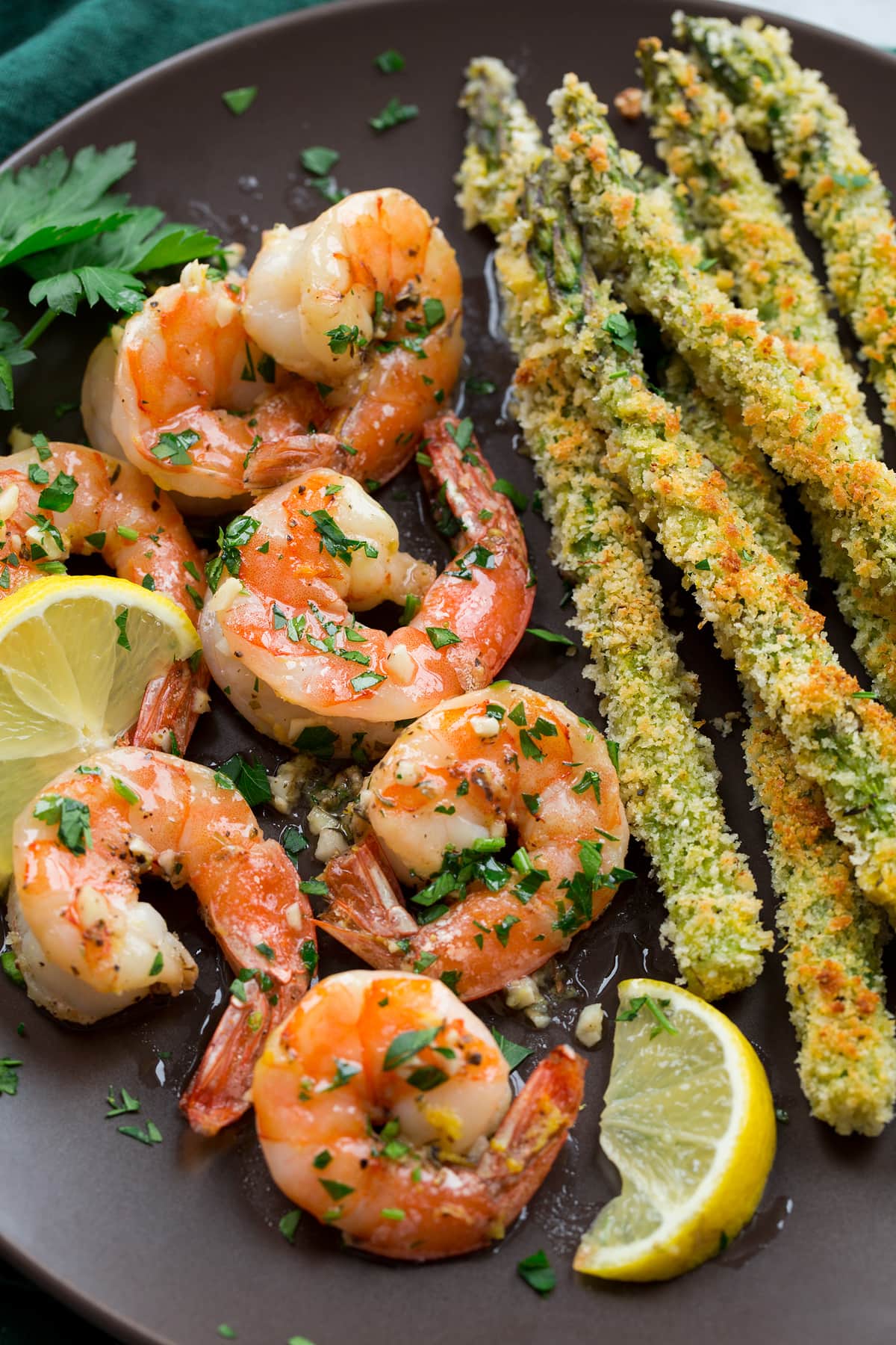 Close up image of shrimp and panko crusted asparagus on a dark brown plate.