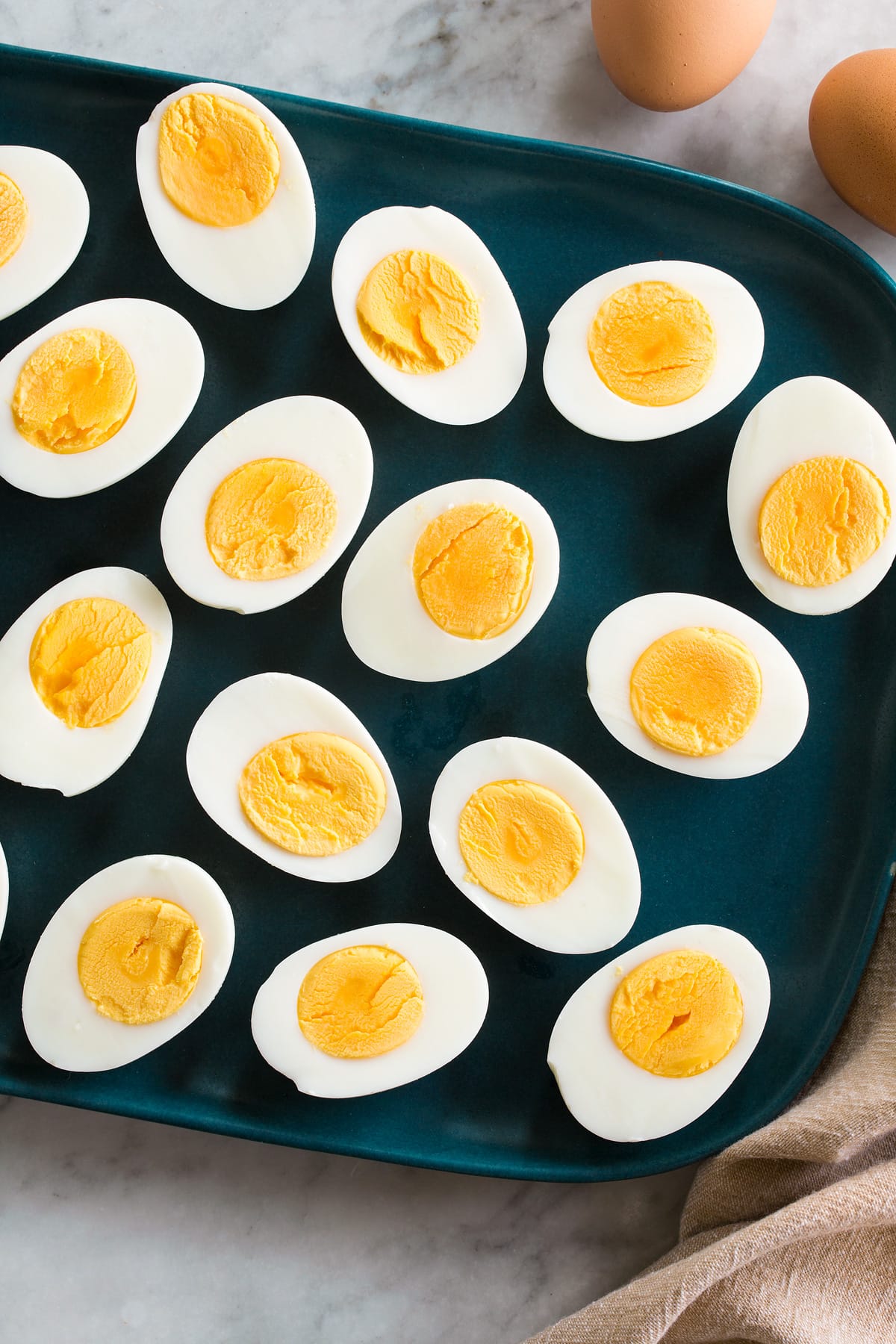 Photo: 15 steamed egg havles in half shown on a blue rectangular platter on a marble surface.