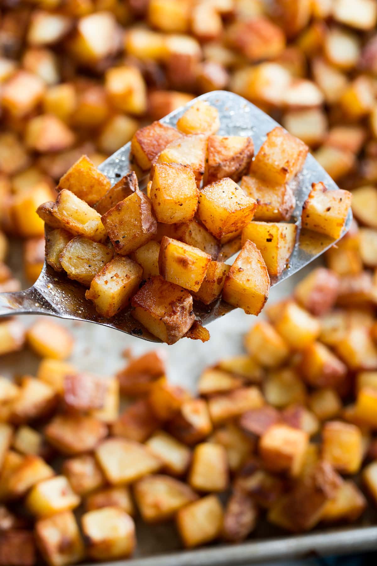 Photo: Close up of breakfast potatoes on a metal spatula.