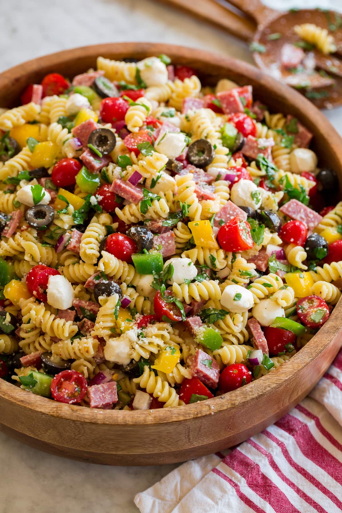 Italian pasta salad shown from a side angle on a large wooden bowl.