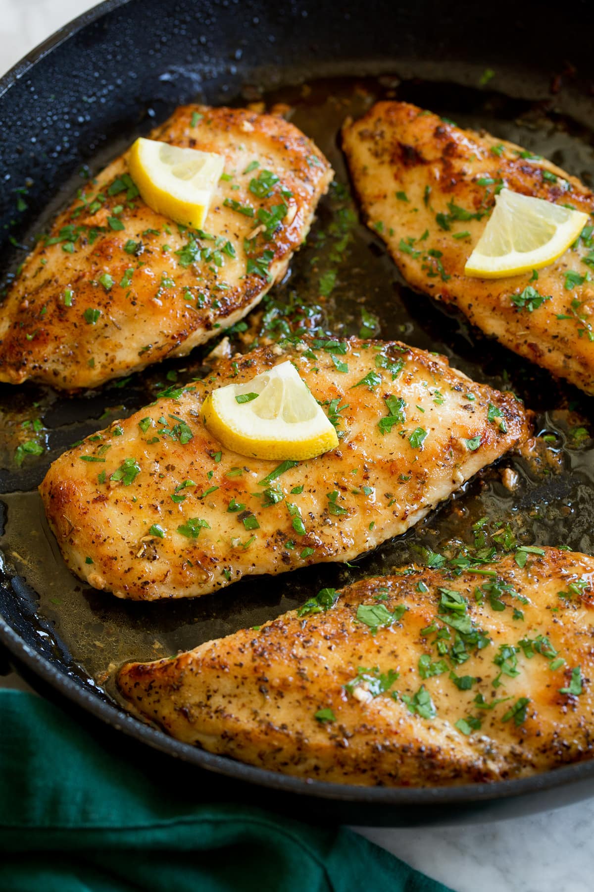 Lemon pepper chicken breasts in a black skillet.