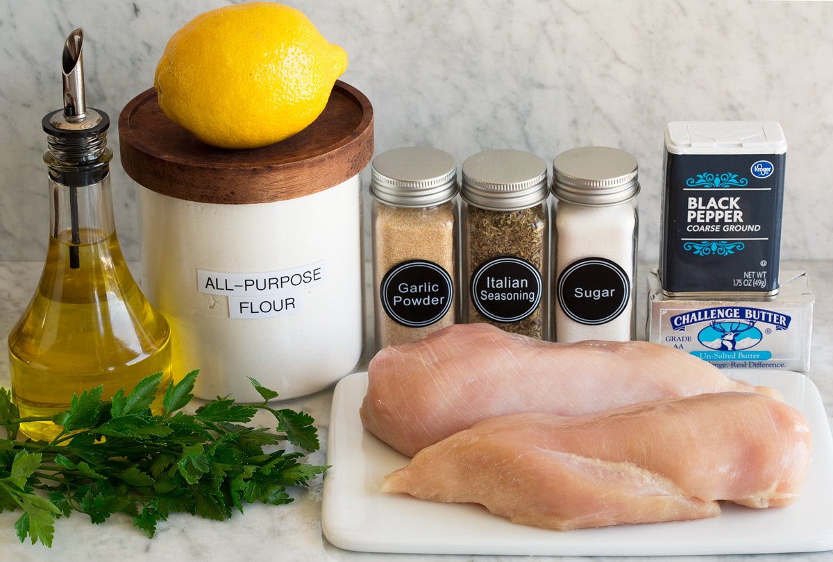 Photo of ingredients used to make lemon pepper chicken. Includes chicken breasts, butter, pepper, sugar, italian seasoning, garlic powder, flour, lemon juice, olive oil, and parsley.