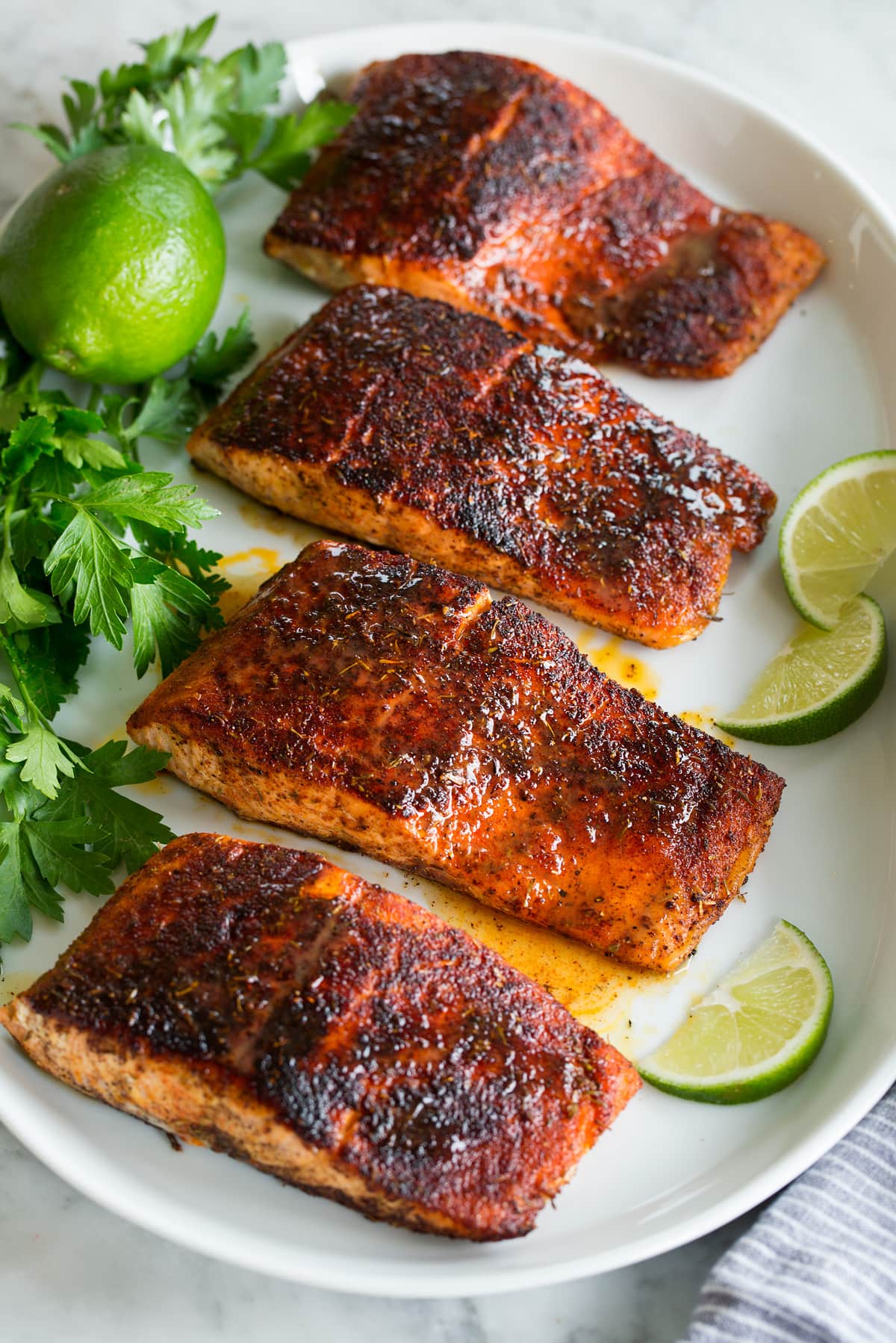 Photo: Blackened salmon shown topped with buttery honey lime sauce. Parsley and limes are shown as garnishes.