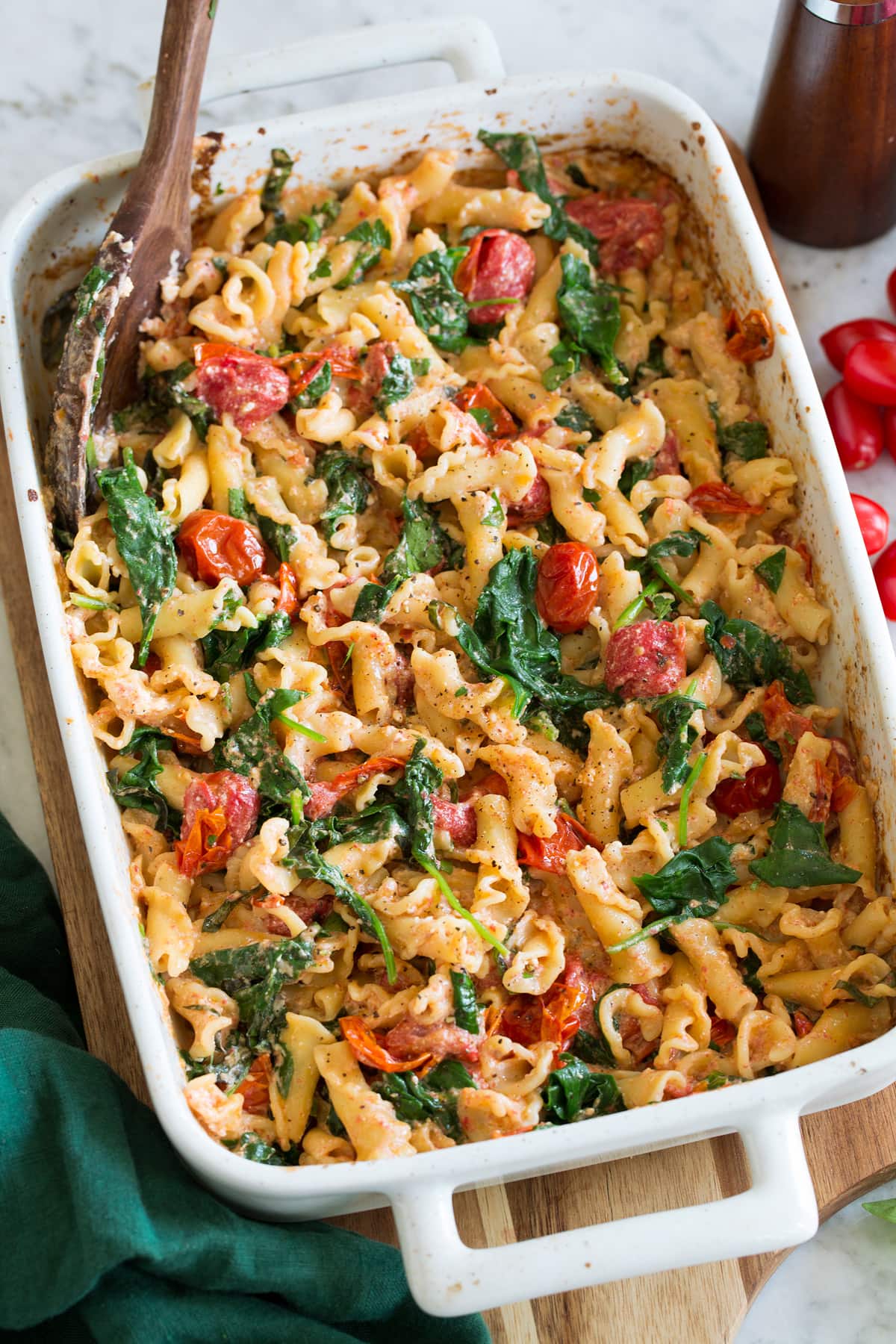 Photo: Baked feta pasta in a white rectangular baking dish shown from a side angle.