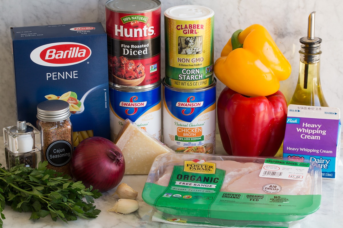 Photo of ingredients. Includes penne pasta, chicken, cream, bell peppers, olive oil, cornstarch, chicken broth, parmesan, tomatoes, red onion, garlic, parsley, salt and pepper.