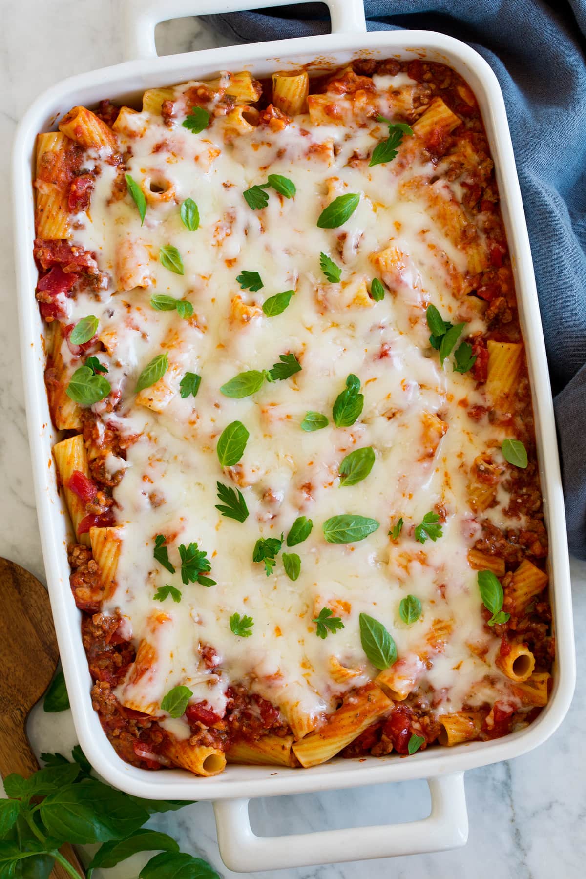 Baked rigatoni shown in a white rectangular ceramic baking dish from above.