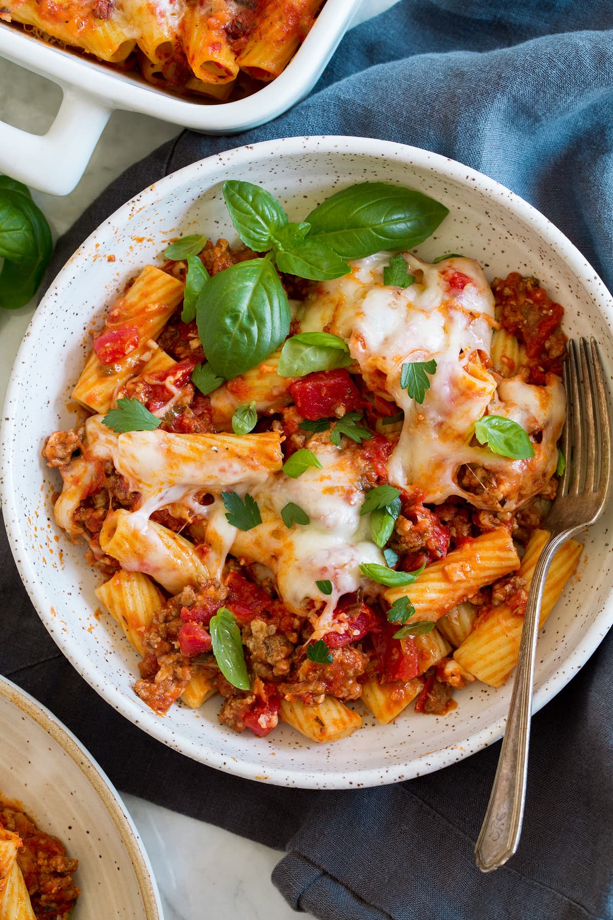 Overhead photo of a serving of baked rigatoni shown in a pasta bowl with a fork.