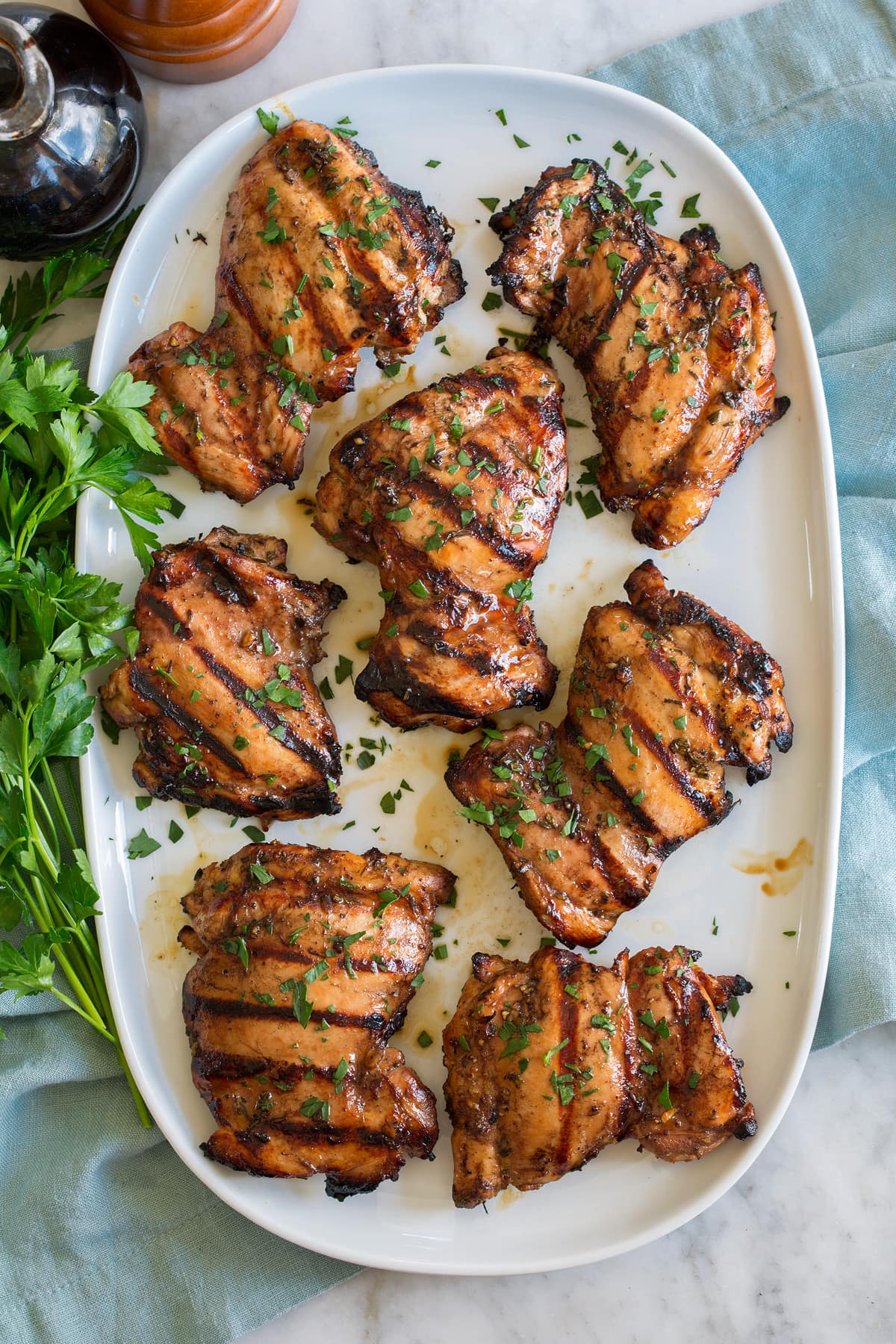 Balsamic chicken thighs shown on an oval white platter from overhead.