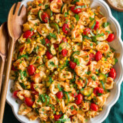 Photo: Tortellini shown in an oval platter from overhead. Platter is on a green cloth on a marble surface.