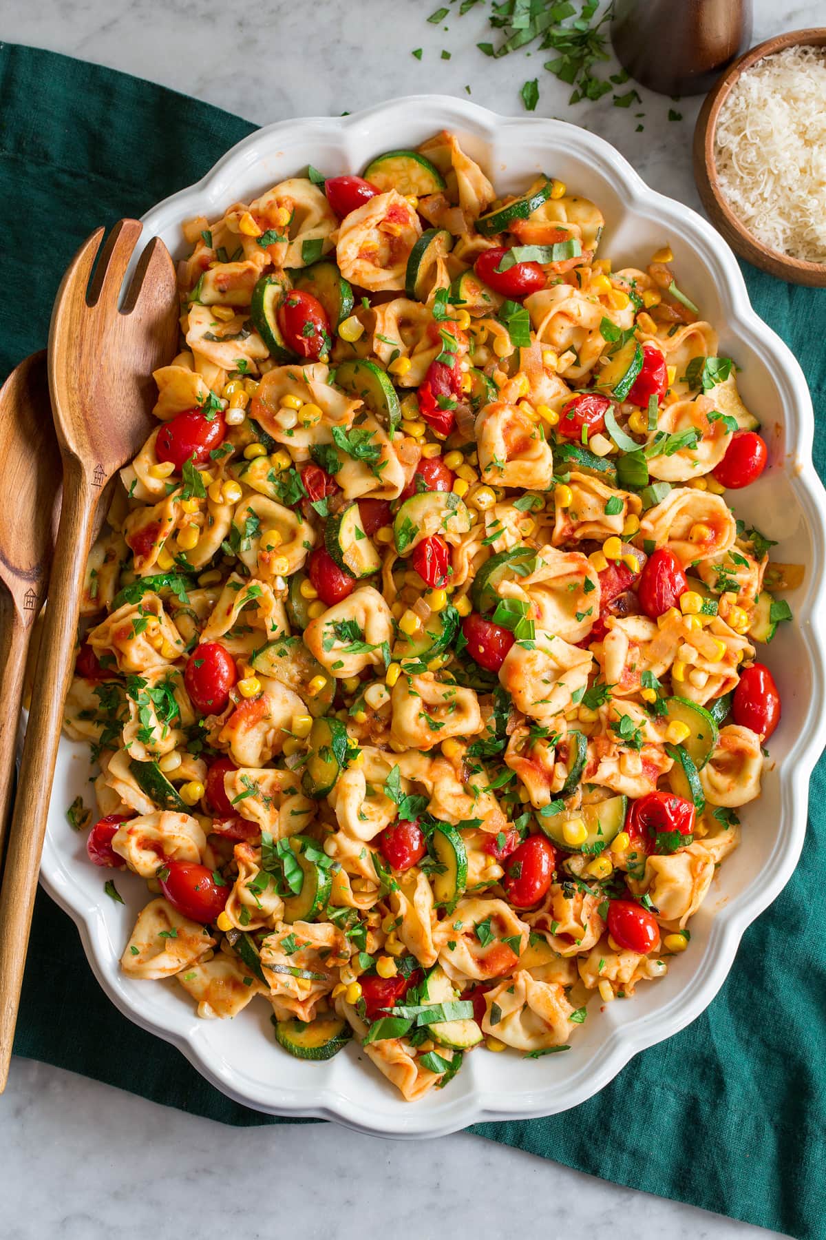 Photo: Tortellini shown in an oval platter from overhead. Platter is on a green cloth on a marble surface.