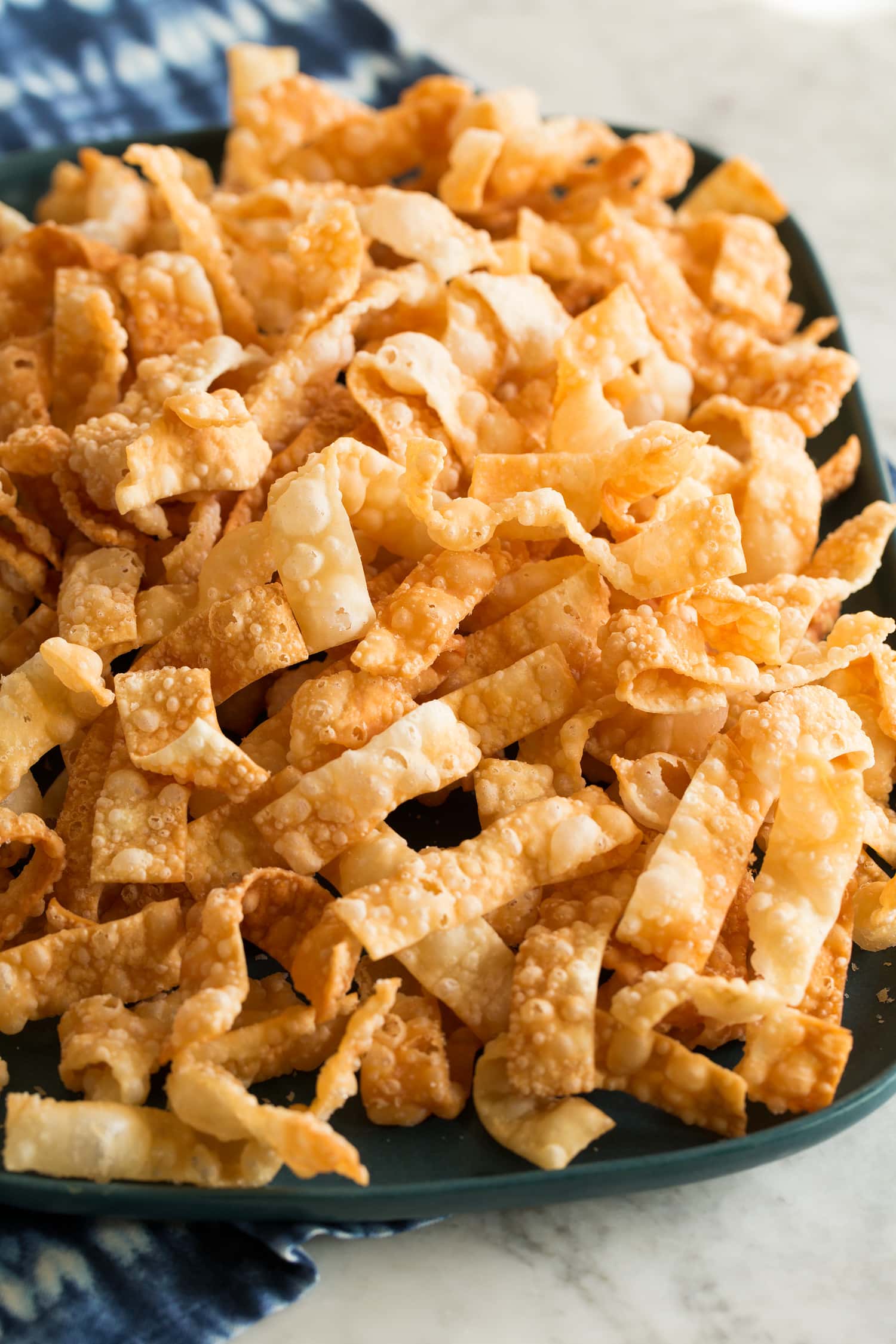 Fried wonton strips piled together on a blue serving platter.