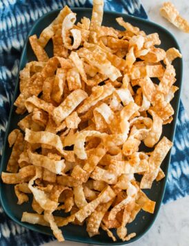 Overhead photo of crispy wonton strips on a rectangular platter.