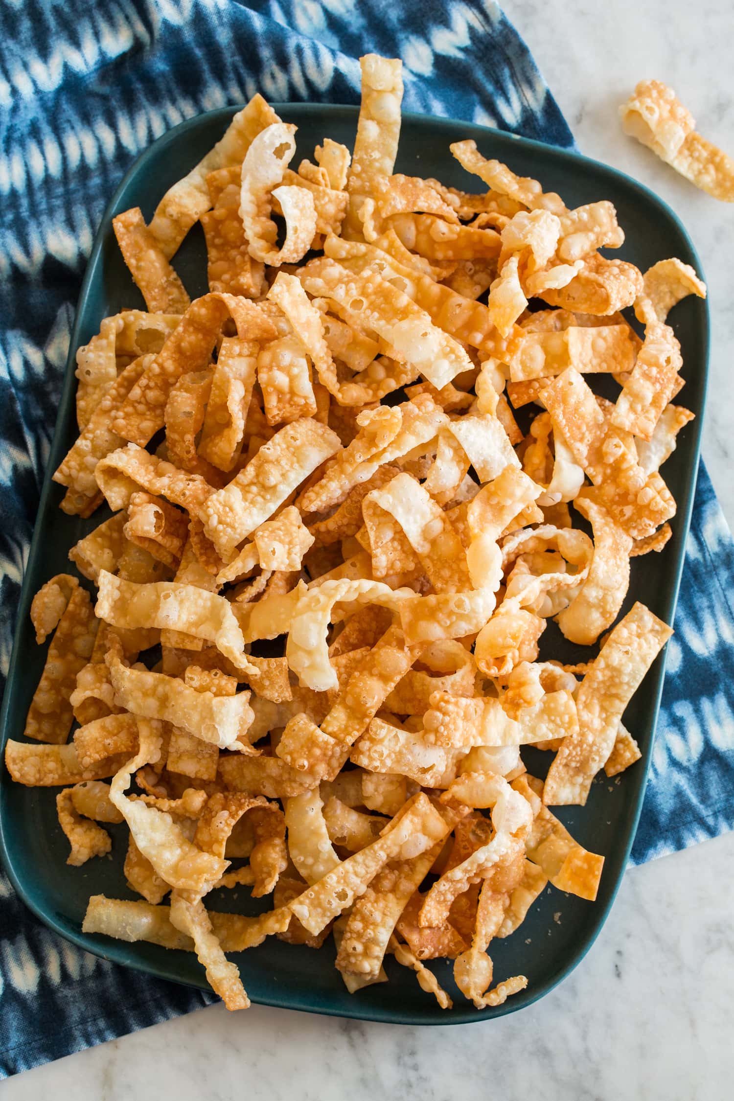 Overhead photo of crispy wonton strips on a rectangular platter.