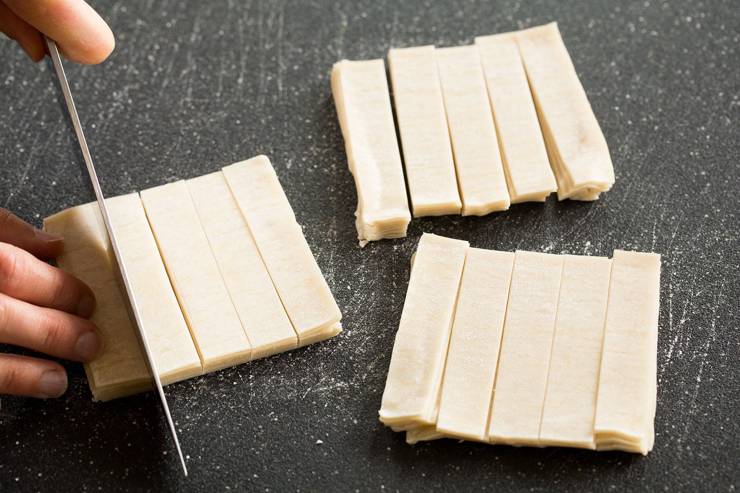 Cutting wontons into strips.