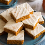 Homemade pumpkin bars stacked on a blue plate.