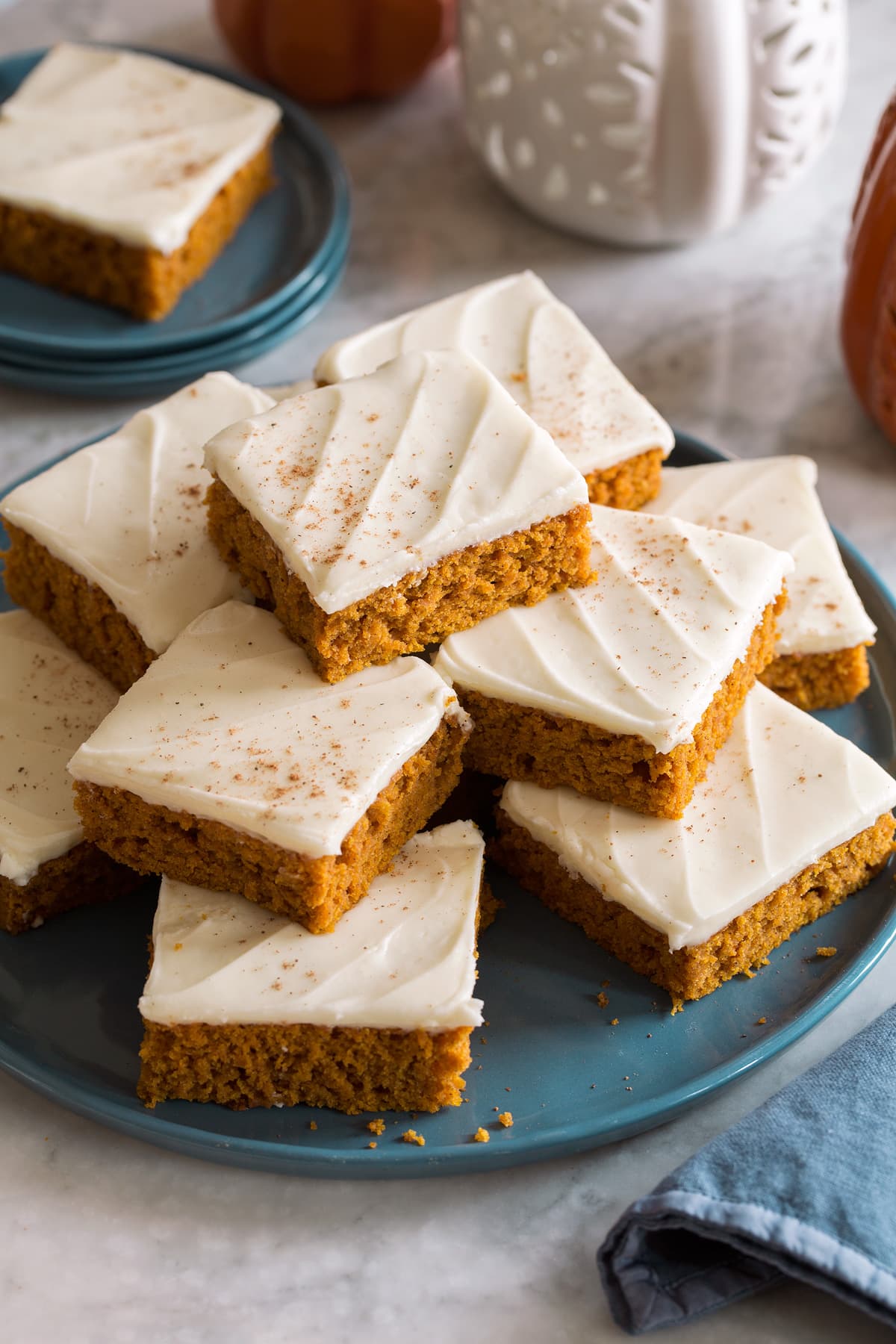 Homemade pumpkin bars stacked on a blue plate.