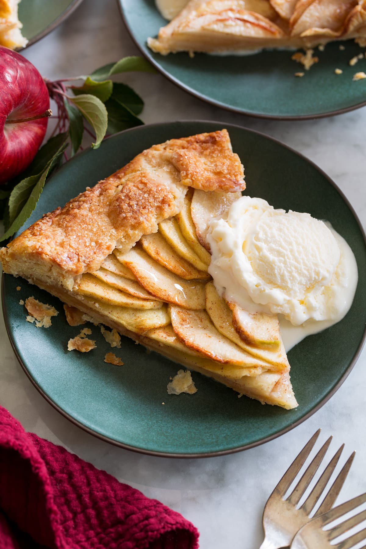 Slice of apple galette shown served with ice cream on a small green dessert plate.