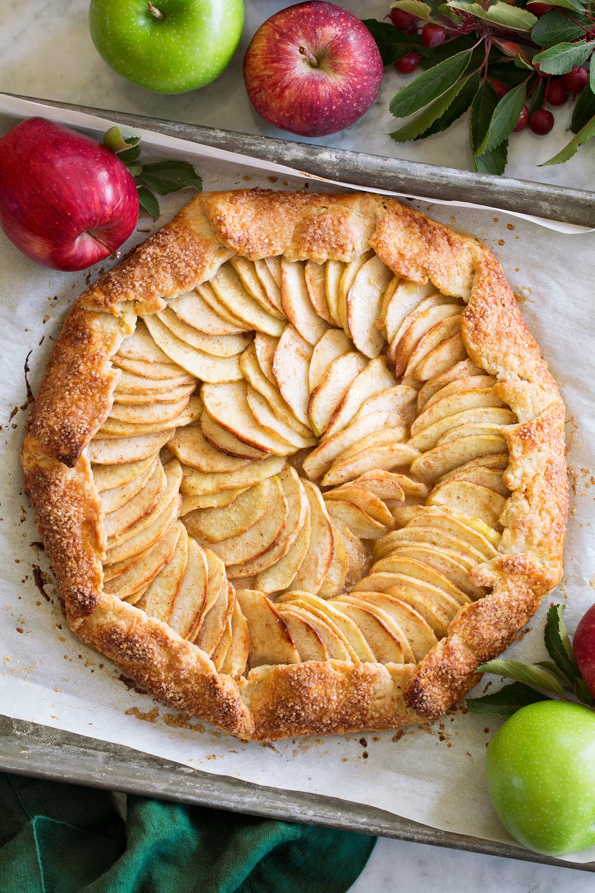 A whole Apple Galette shown from with fresh apples surrounding it.