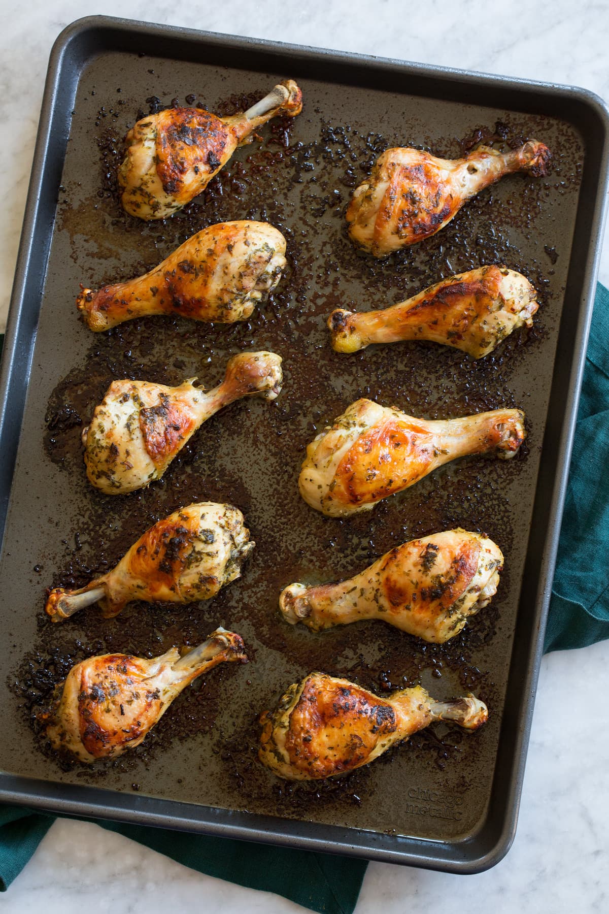 Chicken legs shown on a baking sheet from above, after they're done baking.