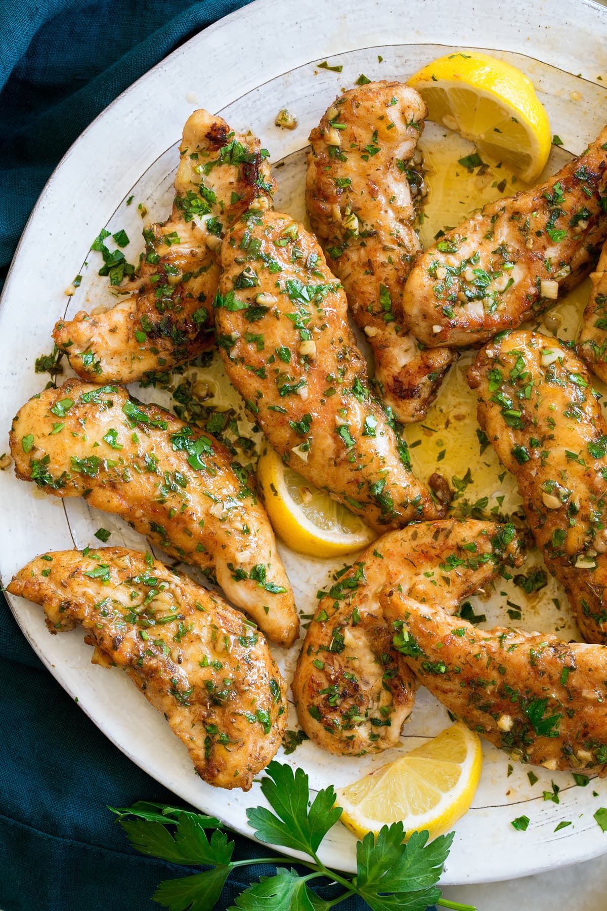 Chicken tenders with a garlic lemon and butter sauce shown on a serving plate.