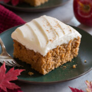 Close up image of single slice of applesauce cake on a green plate with a second slice in the background.