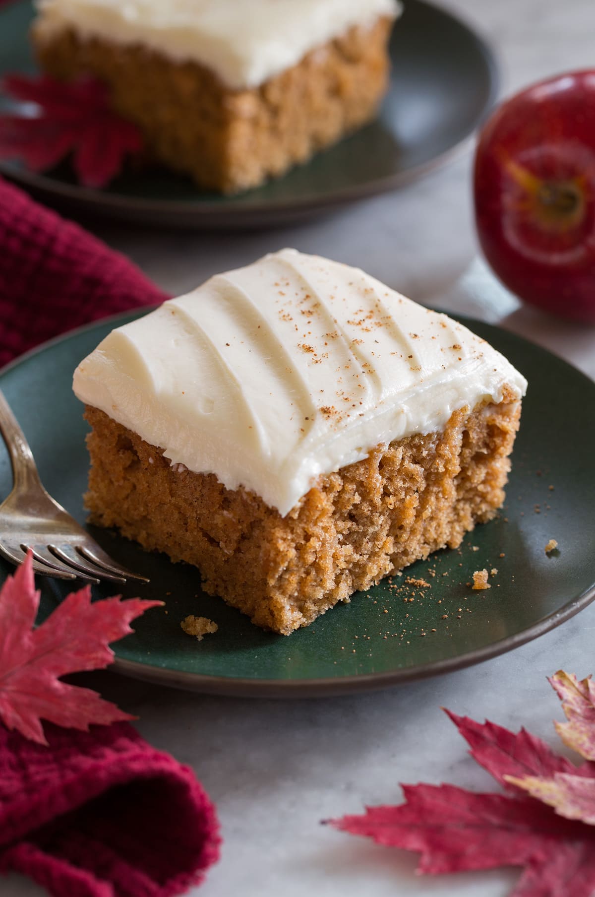 Close up image of single slice of applesauce cake on a green plate with a second slice in the background.