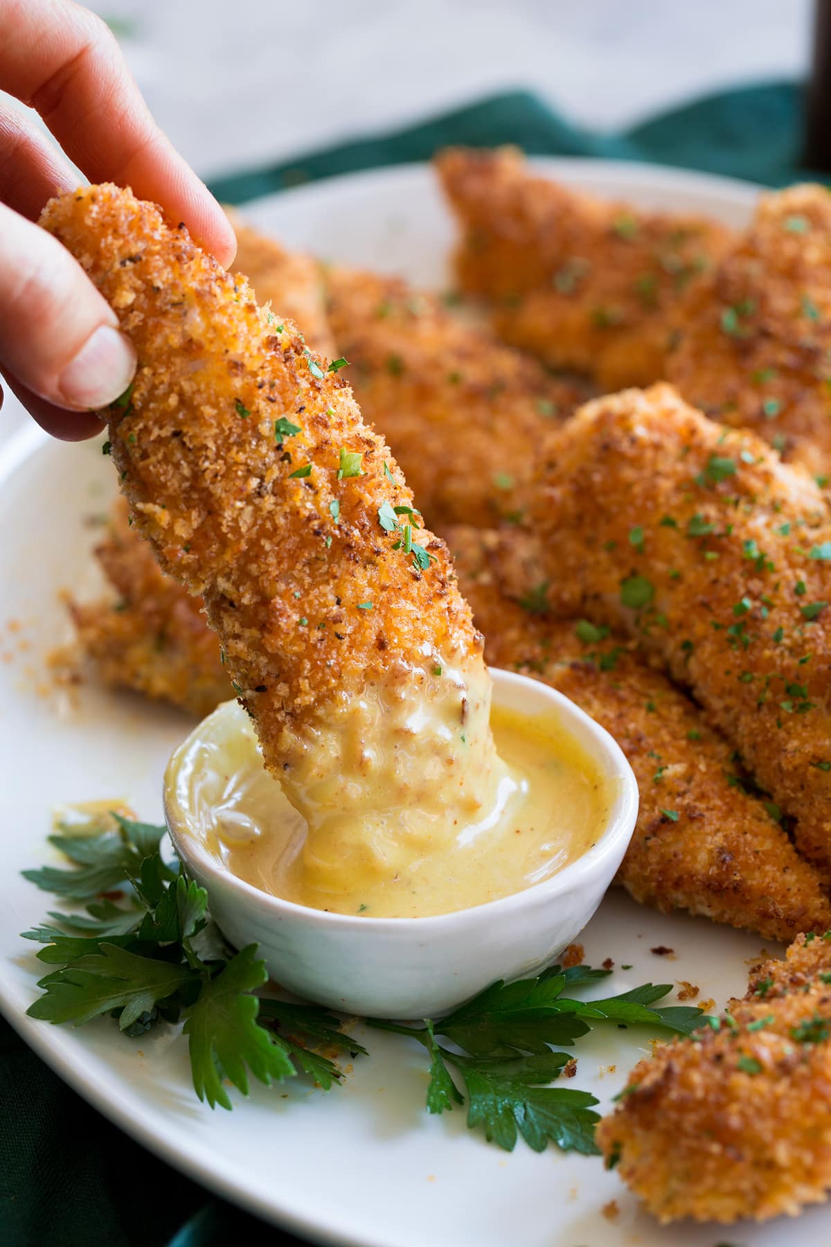 Chicken tender being dipped into honey mustard sauce.