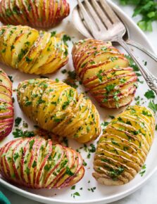 Hasselback Potatoes shown sliced with parmesan and parsley on top.