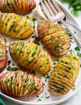 Hasselback Potatoes shown sliced with parmesan and parsley on top.