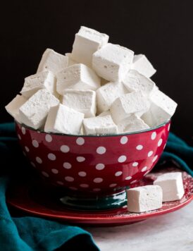 Homemade marshmallows stacked in a red and blue polkadot bowl.