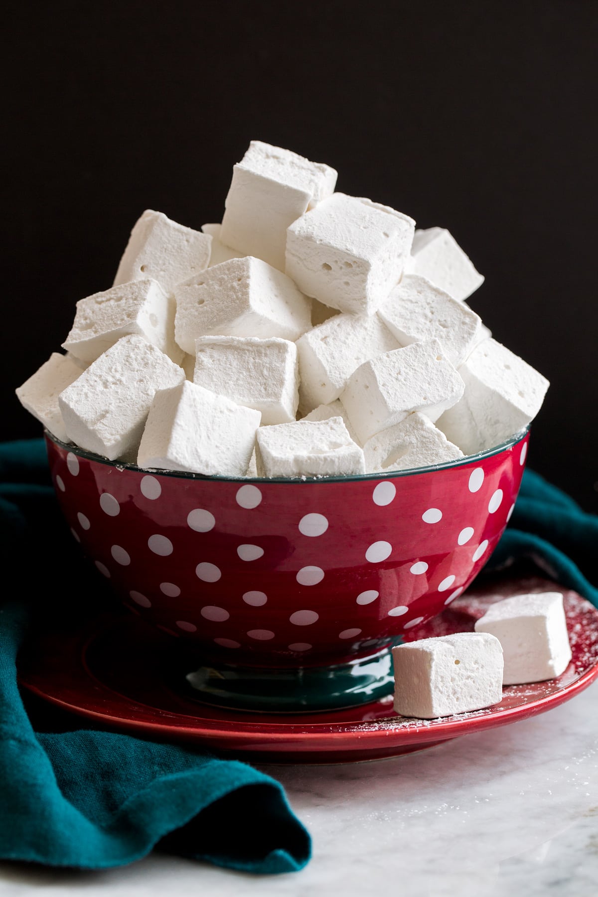 Homemade marshmallows stacked in a red and blue polkadot bowl.